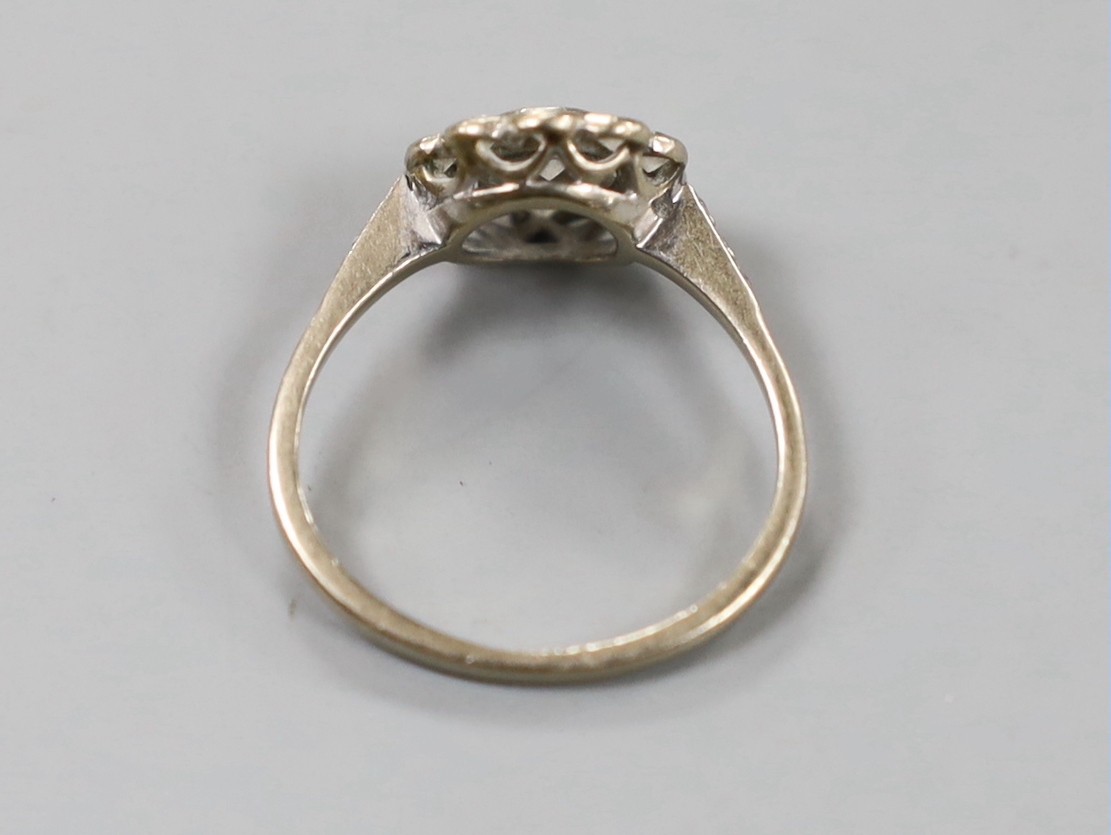 An 18ct white metal and eleven stone diamond set circular cluster ring, size N, gross weight 3.4 grams.